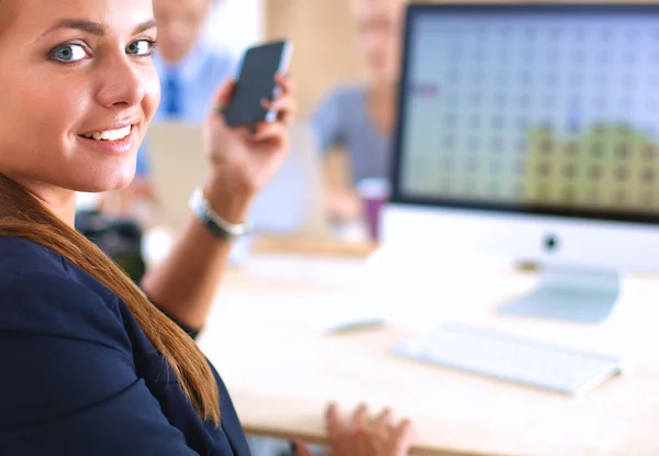 Jonge vrouw werkzaam in kantoor, zit op Bureau, telefoon met — Stockfoto