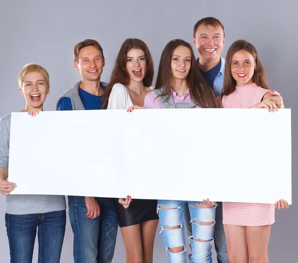 Happy young group of people standing together and holding a blank — Stock Photo, Image