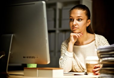 Ofiste çalışan genç bir kadın, masada oturuyor.