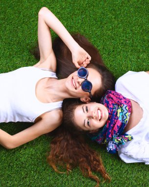 Taze yeşil çimlerin üzerinde yatan iki güzel kız