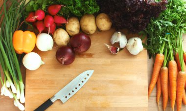 Mutfaktaki masanın üstünde sebzeler var.