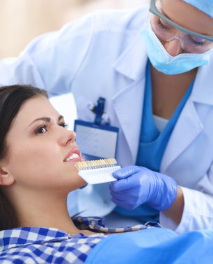 Kadın dişçi hastalarının dişlerinde çalışıyor.