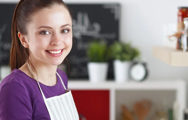 Young woman standing in her kitchen near desk — Stock Photo, Image