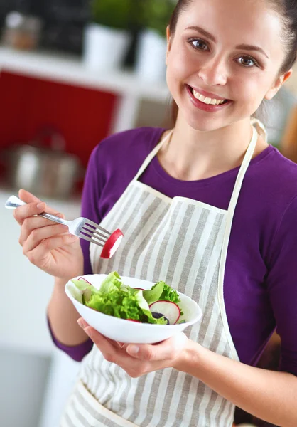 Junge Frau isst frischen Salat in moderner Küche — Stockfoto