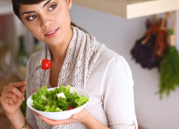 Young woman eating fresh salad in modern kitchen — Stock Photo, Image