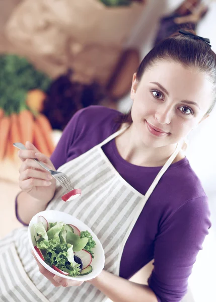 Mujer joven comiendo ensalada fresca en la cocina moderna — Foto de Stock