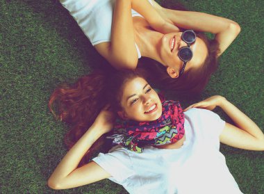 Taze yeşil çimlerin üzerinde yatan iki güzel kız