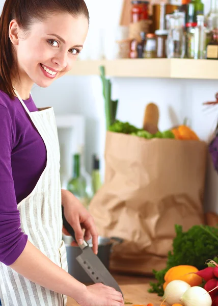 Jonge vrouw die groenten snijdt in de keuken — Stockfoto