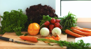 Mutfaktaki masanın üstünde sebzeler var.