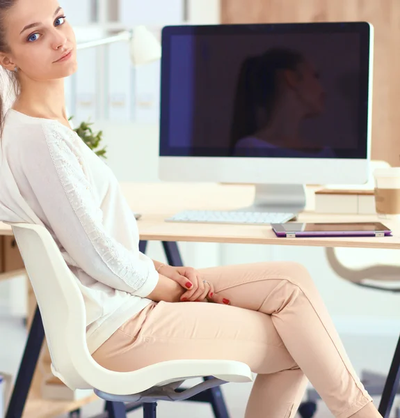Молодая женщина работает в офисе, сидит за столом — стоковое фото