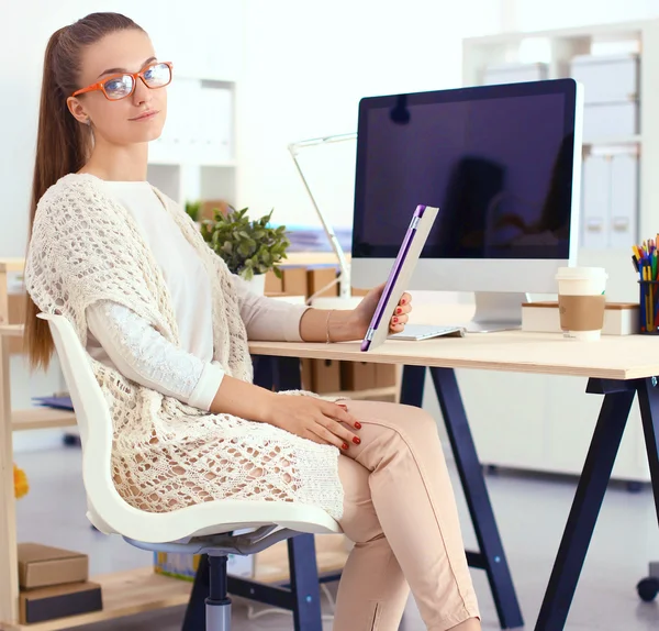 Junge Frau im Büro, am Schreibtisch sitzend — Stockfoto