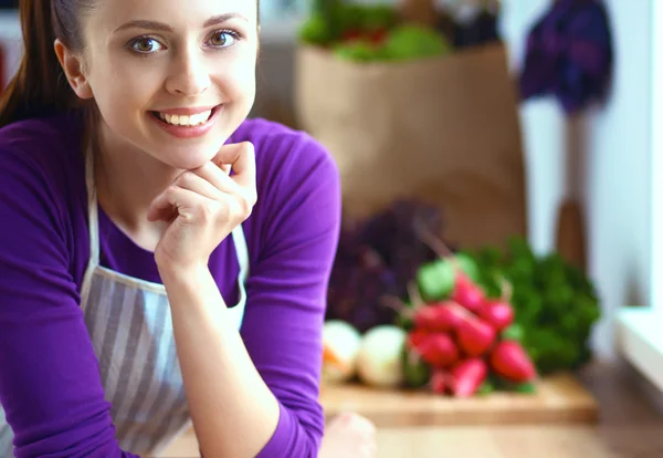 Young woman standing in her kitchen near desk — Stock Photo, Image