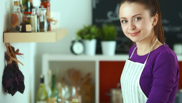 Jovem mulher de pé em sua cozinha perto da mesa com sacos de compras — Fotografia de Stock