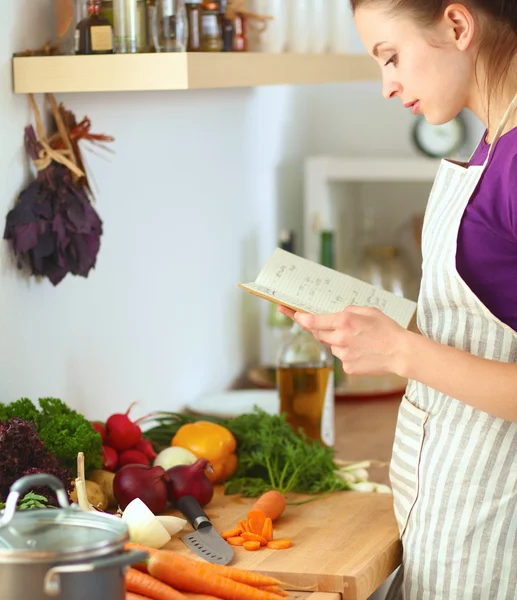 Junge Frau liest Kochbuch in der Küche und sucht Rezept — Stockfoto