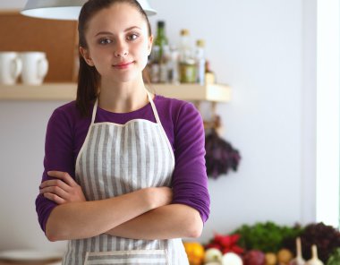 Genç bir kadın mutfakta ayakta.