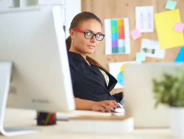 Porträt einer attraktiven jungen Geschäftsfrau, die vor einem Computer sitzt. — Stockfoto