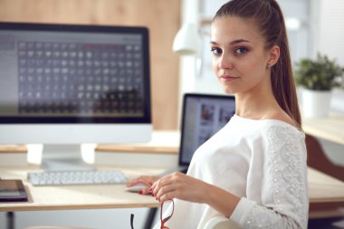 Ofiste çalışan genç bir kadın, masada oturuyor.