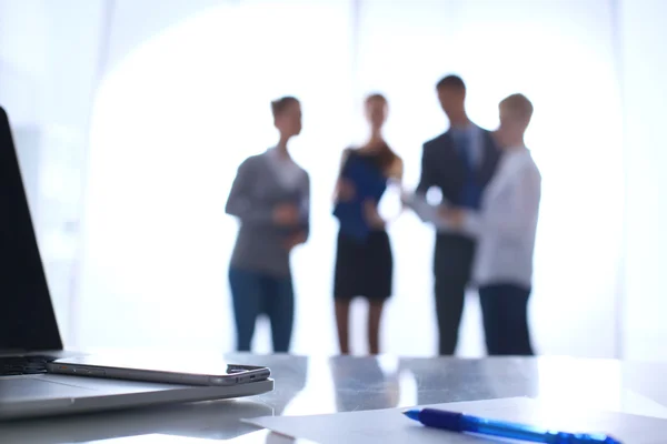 Laptop auf dem Schreibtisch, Geschäftsleute im Hintergrund — Stockfoto