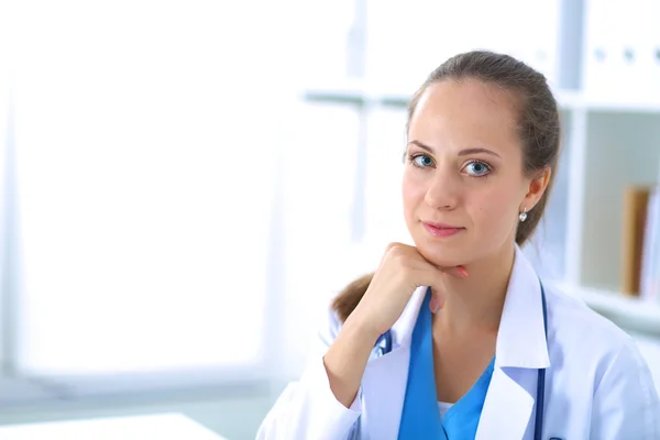 Retrato de uma jovem médica sentada à mesa no hospital — Fotografia de Stock