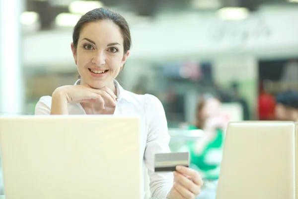 Mujer de negocios sonriente haciendo compras en línea a través de computadora portátil y tarjeta de crédito en la oficina —  Fotos de Stock