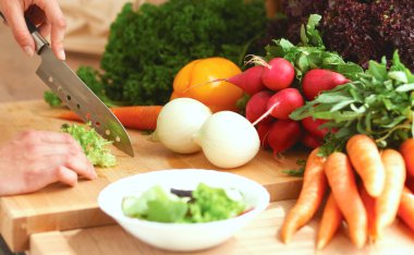 Mutfakta sebze doğrayan genç bir kadın.