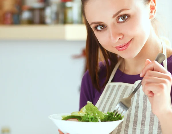 Mladá žena jíst čerstvý salát v moderní kuchyni — Stock fotografie