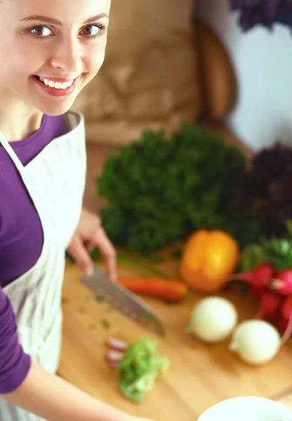 Mujer joven cortando verduras en la cocina — Foto de Stock