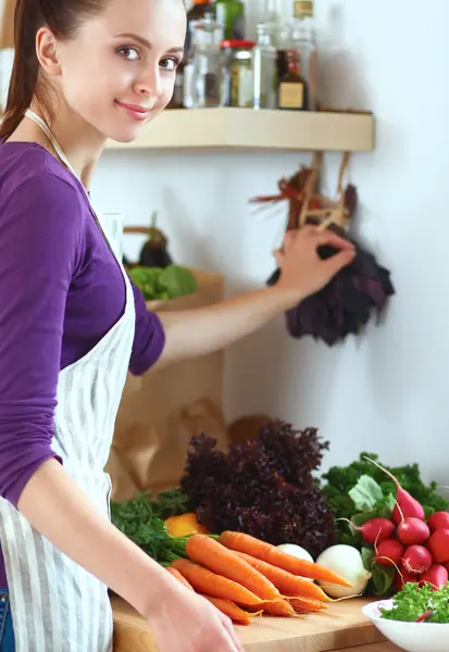 Jonge vrouw die groenten snijdt in de keuken — Stockfoto