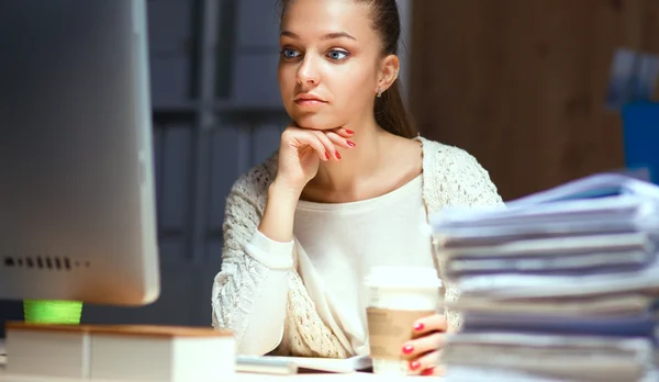 Jeune femme au bureau, assise au bureau et parlant au téléphone — Photo