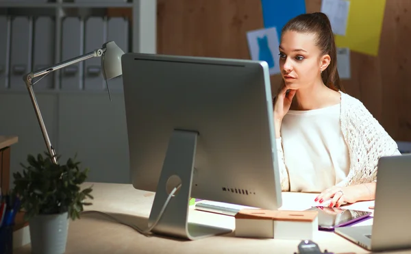 Ung kvinna som arbetar på kontoret, sitter vid skrivbordet — Stockfoto