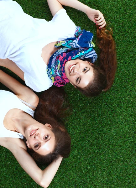 Dos chicas guapas tumbadas en la hierba verde fresca —  Fotos de Stock