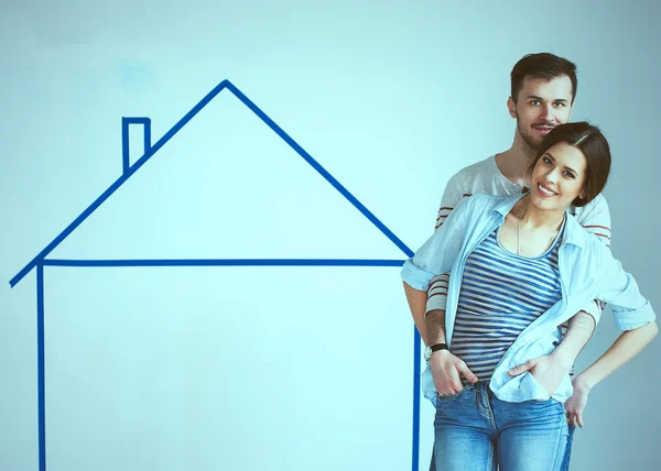 Couple standing in front of painted home on wall — Stock Photo, Image