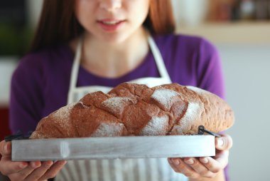 Genç bir kadın mutfağında lezzetli taze ekmek tutuyor.