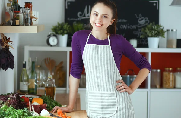 Mujer joven de pie en su cocina cerca del escritorio con bolsas de compras —  Fotos de Stock