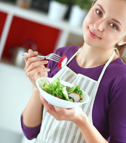 Mujer joven comiendo ensalada fresca en la cocina moderna — Foto de Stock