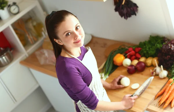 Mujer joven cortando verduras en la cocina — Foto de Stock