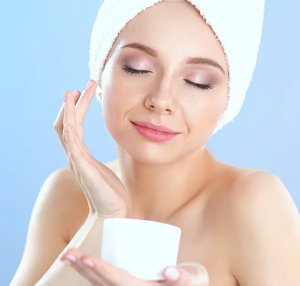 Vacker ung kvinna tillämpa en crème på hennes ansikte isolerad på grå bakgrund — Stockfoto
