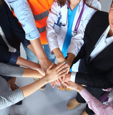 Çeşitli meslekleri olan insanların portresi ellerini birbirinin üstüne koyuyor.