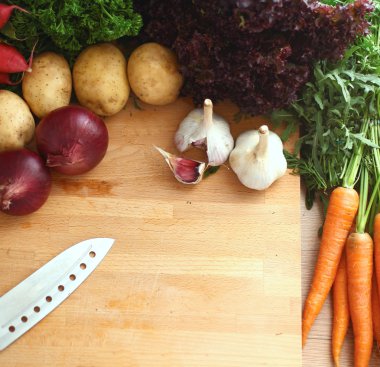 Mutfaktaki masanın üstünde sebzeler var.