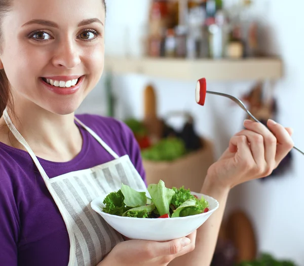 Ung kvinna äter färsk sallad i modernt kök — Stockfoto