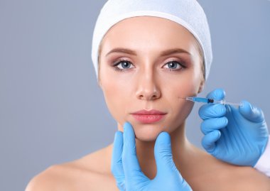 Güzel kadın yüz kozmetik enjeksiyon. Gri arka plan üzerinde izole