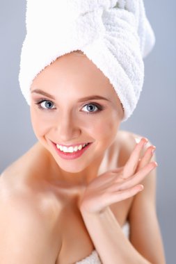 Güzel genç kadın yüzünde gri arka plan üzerinde izole bir krem uygulamak