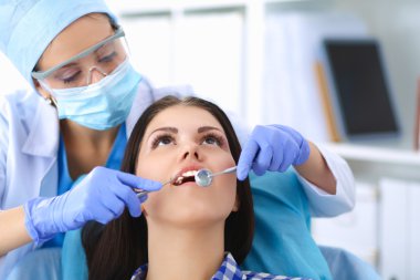 Kadın dişçi hastalarının dişlerinde çalışıyor.