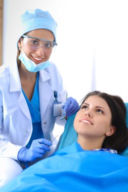 Kadın dişçi hastalarının dişlerinde çalışıyor.