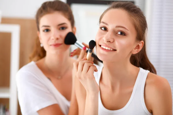 Schöne Mädchen, die in den Spiegel schauen und Kosmetik mit einem großen Pinsel anwenden — Stockfoto