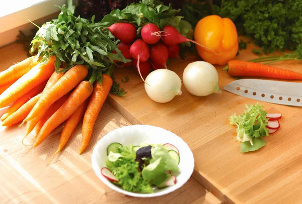 Mujer joven cortando verduras en la cocina — Foto de Stock