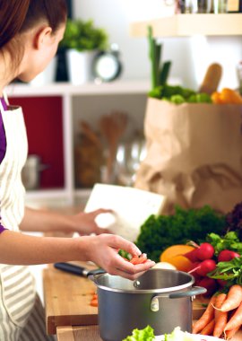 Mutfakta sebze doğrayan genç bir kadın.