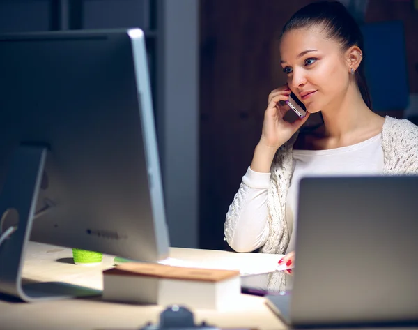 Mujer joven trabajando en la oficina, sentada en el escritorio y hablando por teléfono — Foto de Stock