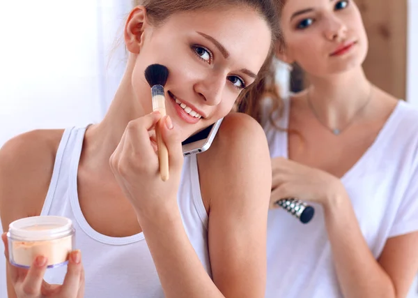 Schöne Mädchen, die in den Spiegel schauen und Kosmetik mit einem großen Pinsel anwenden — Stockfoto