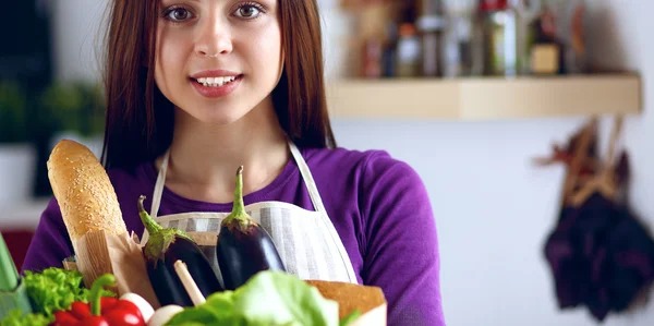 Young woman holding grocery shopping bag with vegetables Standing in the kitchen — Stock Photo, Image